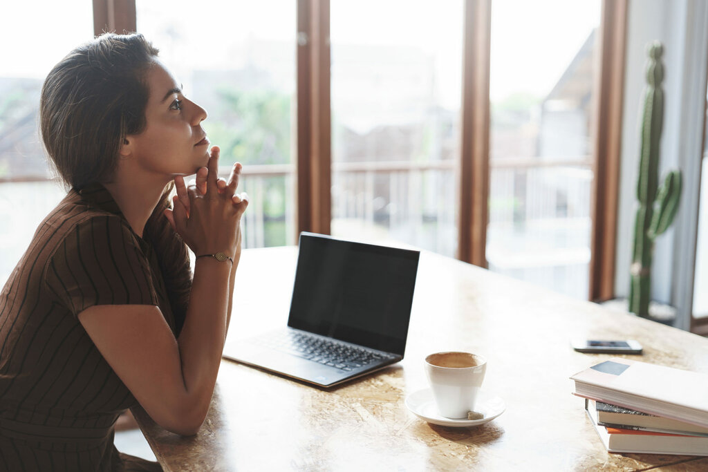 Attractive lucky successful businesswoman listening employees reports sit satisfied pleased near window, laptop opened drink coffee hold hands above chin thoughtful, thinking make decision.