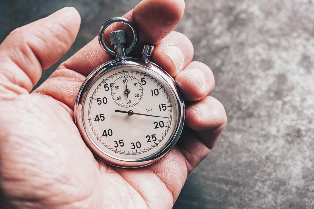 human hand holds a silver stopwatch against a weathered background. ideal for websites and magazines layouts
