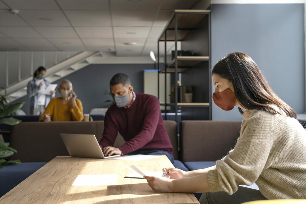 people in the office wearing masks and social distancing