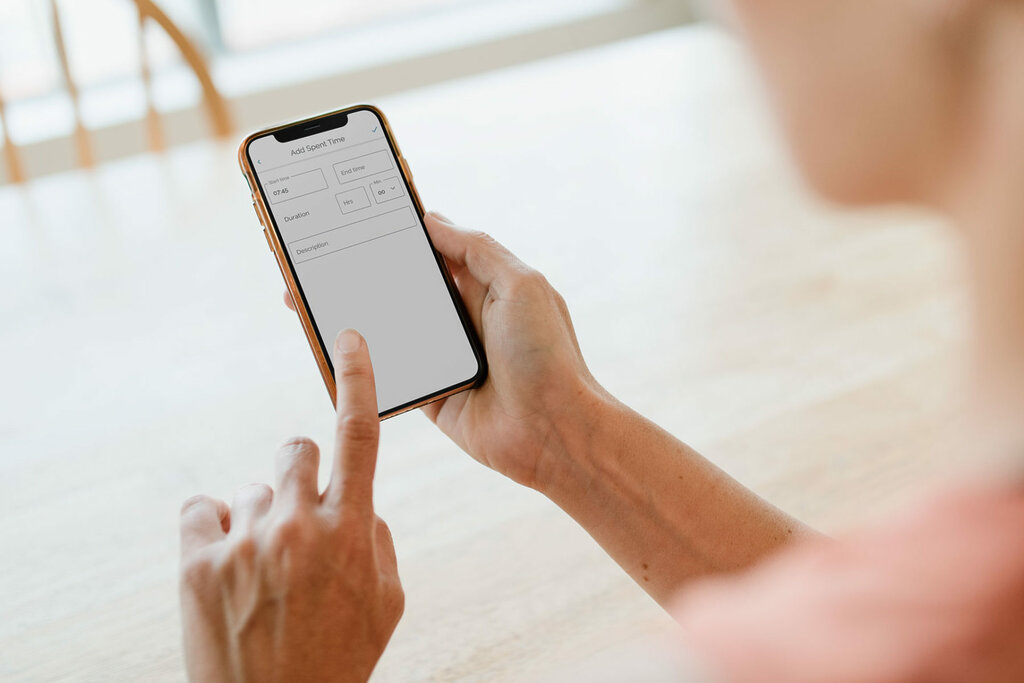 person holding a smartphone and pointing to a time tracking app